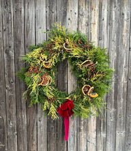 Load image into Gallery viewer, Christmas wreath with greenery, oranges, and a red bow on a wooden background
